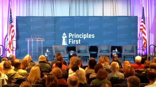 قاعة مؤتمر "المبادئ أولًا" في واشنطن، مع منصة فارغة وأعلام أمريكية، حيث تم إخلاء الحضور بسبب تهديدات أمنية.