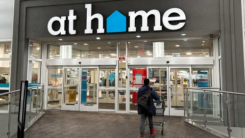 مدخل متجر "At Home" مع شخص يحمل عربة تسوق، يعكس التحديات التي تواجهها الشركة في ظل الإفلاس والتغييرات الاقتصادية.