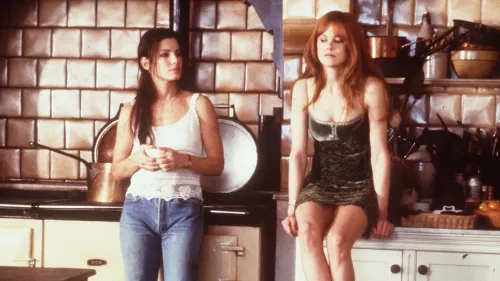 سالي وجيليان أوينز، الشخصيتان الرئيسيتان في فيلم "Practical Magic"، تجلسان في مطبخ مع تفاصيل سحرية تعكس أجواء الفيلم.