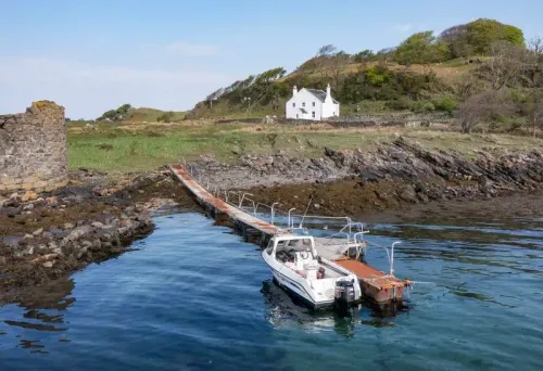 جزيرة شونا الاسكتلندية مع قلعة مدمرة ومركب صغير على الرصيف، تُعرض للبيع مقابل 5.5 مليون جنيه إسترليني.