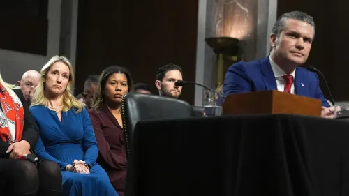 جينيفر هيغسيث، زوجة وزير الدفاع الأمريكي، تجلس بين الحضور خلال جلسة استماع رسمية، تعبيرها يظهر القلق حول المعلومات الحساسة.