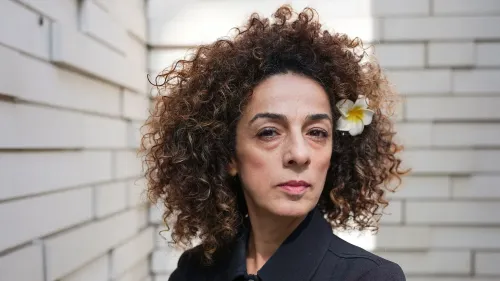 مسيح علي نجاد، صحفية أمريكية من أصل إيراني، تظهر في صورة جادة مع زهرة في شعرها، تعكس شجاعتها في مواجهة التهديدات الإيرانية.