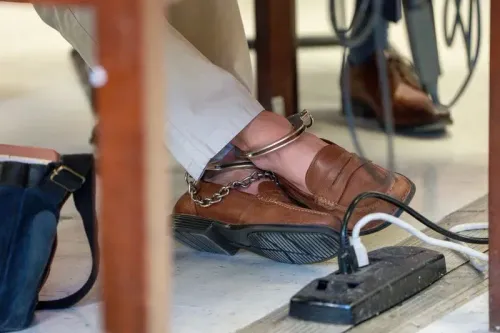 أقدام لويجي مانجيوني المكبلة أثناء مثوله أمام المحكمة، حيث يظهر حذاؤه البني وسلسلة الأصفاد، مما يسلط الضوء على وضعه القانوني.