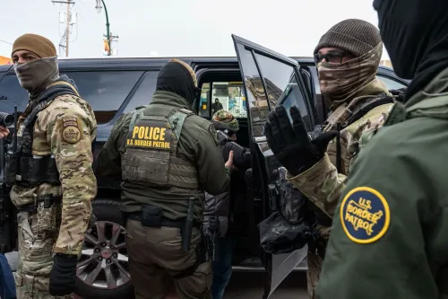 عناصر من شرطة الحدود الأمريكية يرتدون زيًا عسكريًا، أثناء اعتقال شخص بالقرب من مركبة، في سياق مناقشات حول قوانين الهجرة.
