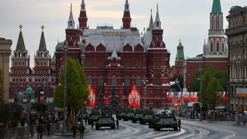 عرض عسكري في موسكو بمناسبة يوم النصر، يظهر المدرعات تسير أمام مبنى تاريخي، مع تزيين الشوارع بالأعلام.