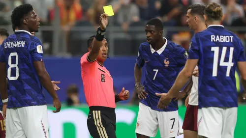 الحكم إيفان بارتون يرفع البطاقة الصفراء خلال مباراة فرنسا في كأس العالم وسط احتجاج لاعبي المنتخب الفرنسي.