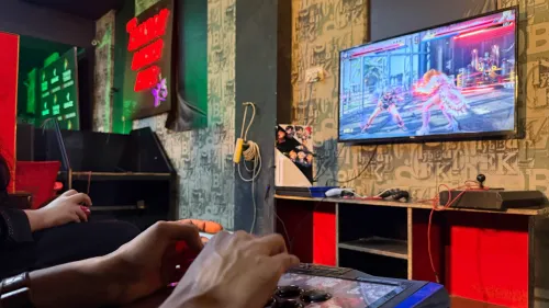 شخصان يلعبان لعبة Tekken في صالة ألعاب في لاهور، مع شاشة تعرض معركة حماسية، مما يعكس ثقافة الألعاب الإلكترونية المتنامية في باكستان.