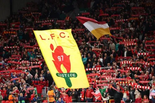 جماهير ليفربول تحمل لافتة كبيرة مكتوب عليها "L.F.C 97 JUSTICE" مع الأوشحة الحمراء، تعبيرًا عن المطالبة بالعدالة لضحايا مأساة هيلزبره.