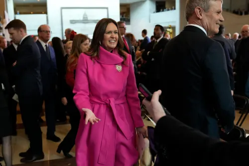 سارة هاكابي، حاكمة أركنساس، ترتدي معطفًا ورديًا وتبتسم أثناء تواجدها في حدث سياسي مع جمهور من الحضور.