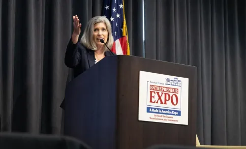 تتحدث مديرة الأعمال الصغيرة كيلي لوفلر في حدث خاص للشركات الصغيرة، مع خلفية العلم الأمريكي، حيث تناقش فرص التعاقد الفيدرالية.