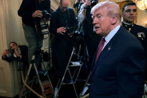 الرئيس دونالد ترامب يتحدث في حدث رسمي، محاطًا بالصحفيين والمصورين، مما يعكس الضغوط السياسية المرتبطة بقضايا الهجرة.