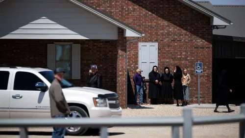 مجموعة من الأشخاص يرتدون ملابس تقليدية، يقفون أمام منزل من الطوب في ولاية تكساس، في سياق تفشي مرض الحصبة.