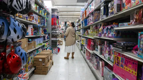 امرأة تتجول في ممر متجر مليء بالألعاب والسلع المتنوعة، مما يعكس انتعاش مبيعات التجزئة في الولايات المتحدة.