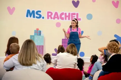 تظهر "الآنسة راشيل" في عرض للأطفال، حيث تتفاعل مع مجموعة من الأطفال الذين يجلسون أمامها، مما يعكس أهمية البرامج التعليمية في الأبوة.