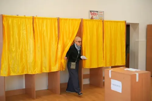 امرأة تخرج من كشك اقتراع في مركز انتخابي، حيث تجري الانتخابات الرئاسية الرومانية وسط أجواء سياسية متوترة.