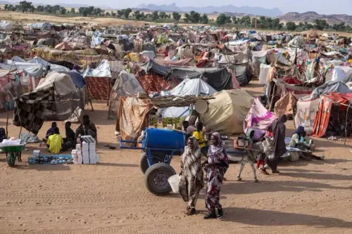 مخيم للنازحين في السودان، حيث تظهر الخيام المتعددة والأشخاص الذين يتنقلون بين الممرات، وسط ظروف إنسانية صعبة.