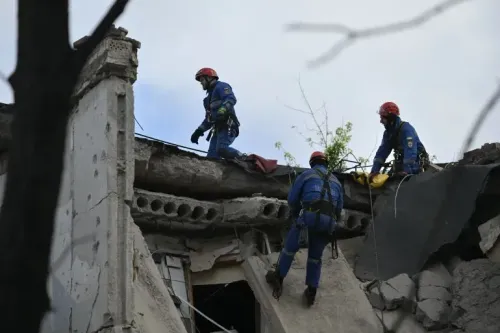 رجال إنقاذ يرتدون خوذات حمراء يقومون بعمليات البحث والإنقاذ على سطح مبنى مدمر في أوكرانيا بعد هجوم بطائرة مسيرة.