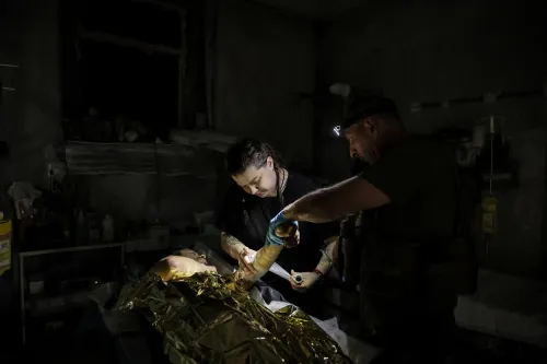 أطباء يعالجون مصابًا في غرفة مظلمة، يظهرون تركيزهم في تقديم الإسعافات الأولية خلال الصراع في شرق أوكرانيا.