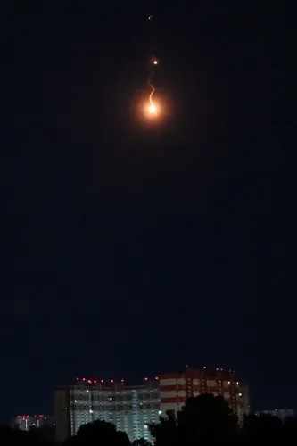 صورة تظهر سماء كييف ليلاً مع توهج ناري، يُحتمل أنه نتيجة هجوم بطائرات مسيرة، بينما تُرى مباني سكنية في الأسفل.