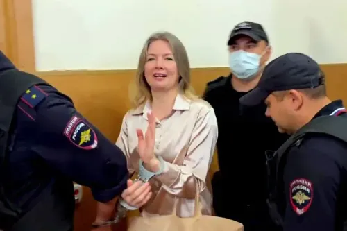 حكم على الصحفية أولغا كومليفا بالسجن 12 عامًا بتهمة "التطرف"، بينما تظهر وهي تبتسم وتلوح من داخل قاعة المحكمة.