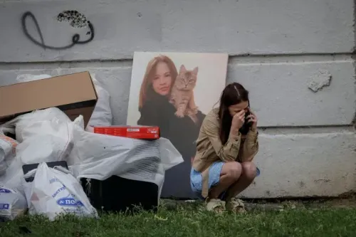 امرأة تجلس بجانب أكوام من النفايات، تتحدث بهاتفها، بينما خلفها صورة لامرأة تحمل قطة، تعكس تأثير الحرب في أوكرانيا.