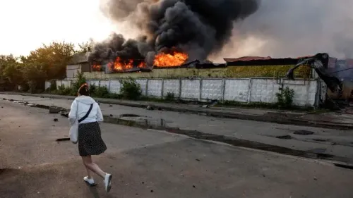 امرأة تسير نحو مبنى محترق، مع تصاعد الدخان الأسود والنيران، في مشهد يعكس آثار الهجمات الروسية على أوكرانيا.