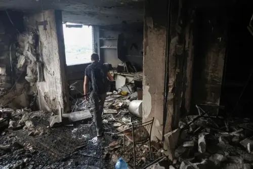 رجل يسير في غرفة مدمرة بفعل القصف، حيث تظهر آثار الدمار والأثاث المتناثر، مما يعكس تأثير الحرب في أوكرانيا.