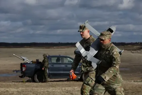 جنود يحملون طائرات مسيرة في منطقة مفتوحة، مع وجود مركبة عسكرية في الخلفية، في إطار تدريبات عسكرية مرتبطة بالصراع الأوكراني.