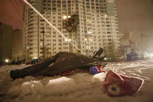 صورة تظهر شخصًا مغطى في الثلوج بعد هجوم روسي على مدينة أوكرانية، مع خلفية لمبنى سكني مضاء في الليل.