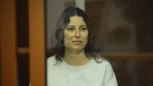 كسينيا كاريلينا، الأمريكية الروسية، تظهر مبتسمة خلف زجاج أثناء محاكمتها، بعد إطلاق سراحها من السجن في روسيا.