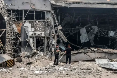دمار واسع في مبنى صناعي في كييف بعد هجوم صاروخي روسي، مع وجود أشخاص يتفقدون الأضرار وسط أنقاض الحطام.
