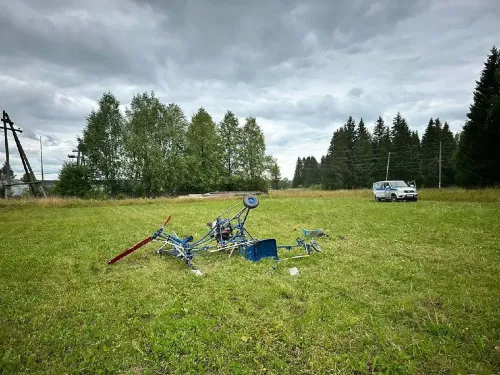 حطام مروحية محلية الصنع في حقل، بعد محاولة فاشلة للإقلاع، مع وجود سيارة في الخلفية، تعكس شغف المخترع فلاديمير ترابيزنيكوف.