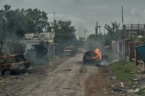 شارع مدمر في بلدة بوكروفسك، تظهر فيه سيارات محترقة وأدخنة تتصاعد، مما يعكس آثار الصراع المستمر في شرق أوكرانيا.