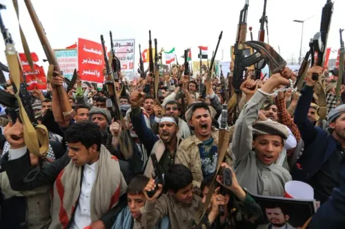 مسلحون حوثيون يرفعون أسلحتهم ويهتفون خلال مظاهرة في اليمن وسط تصاعد النزاع مع السعودية.