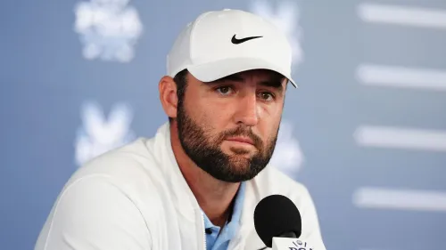 صورة للاعب جولف خلال مؤتمر صحفي، يظهر تعبيره الجاد وهو يرتدي قبعة ونظرة تأملية، مما يعكس الضغوط التي يواجهها في مسيرته الرياضية.