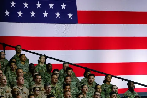 مجموعة من الجنود الأمريكيين يجلسون أمام علم الولايات المتحدة الكبير، في سياق مناقشات حول قانون السياسة الدفاعية.