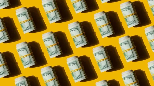 أكوام من الدولارات الملفوفة بشريط مطاطي على خلفية صفراء، تمثل استراتيجيات الادخار والتخطيط المالي للتقاعد.