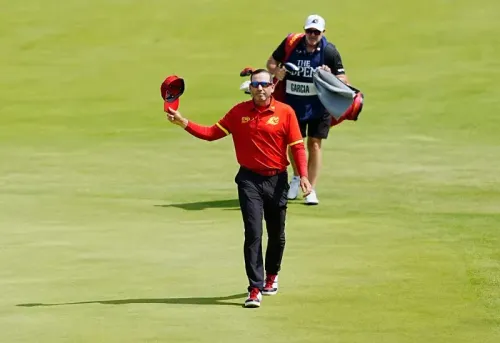 سيرجيو غارسيا، لاعب الجولف الإسباني، يرفع قبعته بعد جولة في البطولة المفتوحة، بينما يتبعه مساعده حاملاً حقيبته.