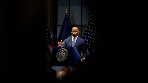 خطاب عمدة مدينة نيويورك إريك آدامز خلال مؤتمر صحفي، مع علمين أمريكيين خلفه، وسط أجواء مشحونة بالتوترات القانونية.