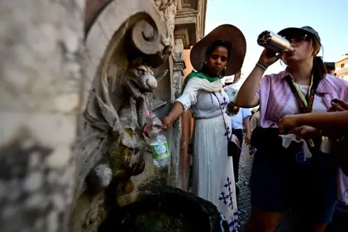 سياح في روما يتزودون بالمياه من نافورة عامة لتجنب الحرارة الشديدة، مع درجات حرارة تتجاوز 40 درجة مئوية.