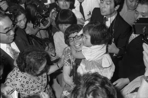 جونكو تاباي وسط حشد من الناس، تحتفل بإنجازها كأول امرأة تتسلق قمة إيفرست، مع طفلة تعانقها، بينما تلتقط الكاميرات اللحظة التاريخية.