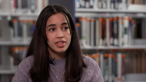 أليشا أورتيز، 19 عامًا، تتحدث عن تحدياتها في التعليم والأمية، مع خلفية من الكتب في المكتبة.