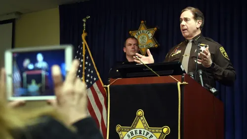 عمدة مقاطعة أوكلاند يتحدث في مؤتمر صحفي حول حالة الأطفال المهجورين، مع وجود ضابط شرطة خلفه.