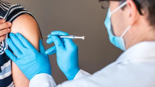 تظهر الصورة شخصًا يتلقى لقاح الهربس النطاقي من طبيب يرتدي قفازات زرقاء، مما يبرز أهمية التطعيم في الوقاية من الأمراض القلبية.