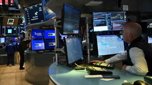 متداول في سوق الأسهم الأمريكية يراقب شاشات عرض البيانات المالية، مع تزايد القلق بشأن التضخم وأداء الأسواق.