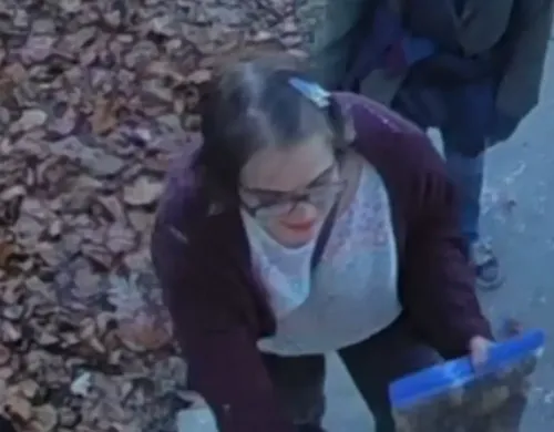 امرأة شابة تحمل علبة زرقاء، تظهر في حي سكني محاط بأوراق الشجر المتساقطة، في سياق قضية "سليندر مان" الشهيرة.