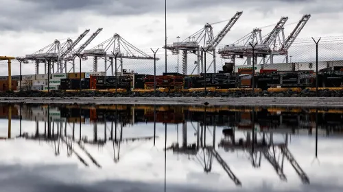 صورة لميناء يحتوي على رافعات وشاحنات، تعكس تأثير التعريفات الجمركية على التجارة الدولية.