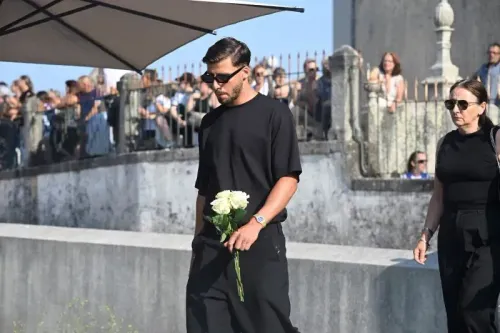 حضور شخص يرتدي ملابس سوداء ويحمل وردة بيضاء في جنازة نجم كرة القدم الراحل ديوجو جوتا، مع وجود معزين في الخلفية.