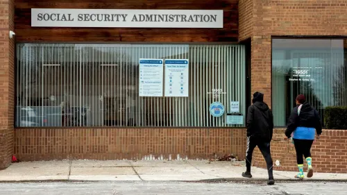 واجهة مكتب إدارة الضمان الاجتماعي، حيث يتجه شخصان نحو المدخل. تعكس الصورة التحديات المتعلقة بمعالجة مطالبات التقاعد المتزايدة.