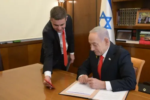 رئيس الوزراء الإسرائيلي بنيامين نتنياهو يوقع وثيقة، بينما يشاركه أحد مساعديه، مع العلم الإسرائيلي خلفهما، في سياق الاعتراف بأرض الصومال.